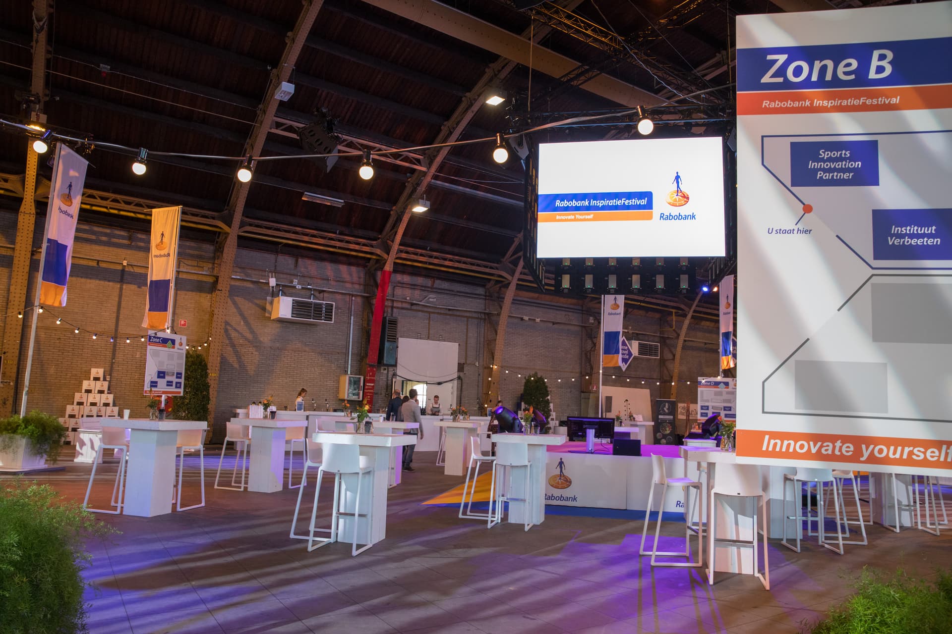 Statafels en sfeerverlichting in een evenementenhal
